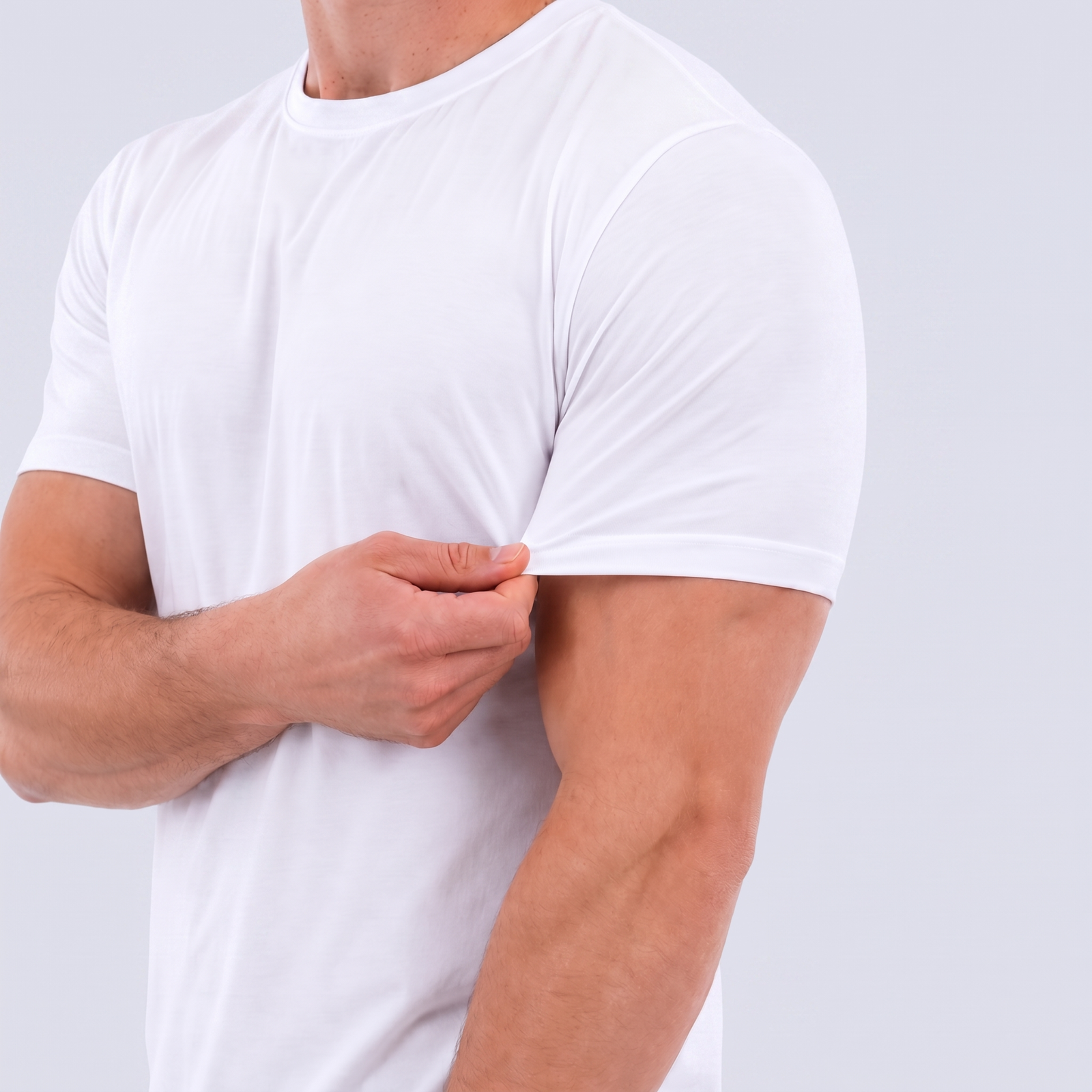 A close-up of a man wearing a white short-sleeve stretch gym tee, pulling the sleeve slightly to show the fabric stretch and fit, against a light gray background.